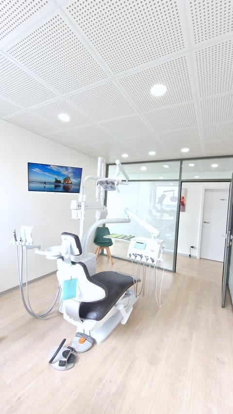 Salle de soins avec fauteuil dentaire KaVo, plafond acoustique et cloison vitrée