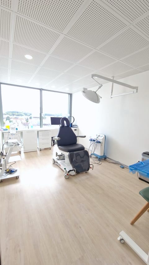 Salle de chirurgie avec fauteuil patient, scialytique et vue sur la ville